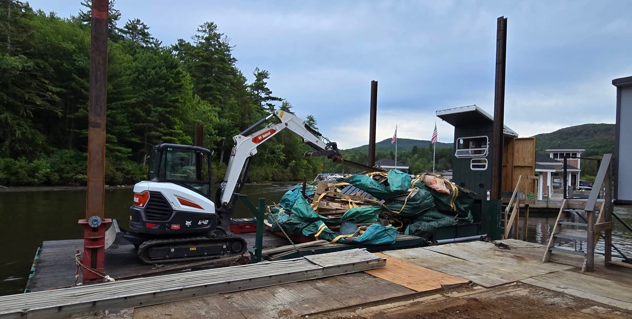 Bobcat skid steer on a working dock with a green barge