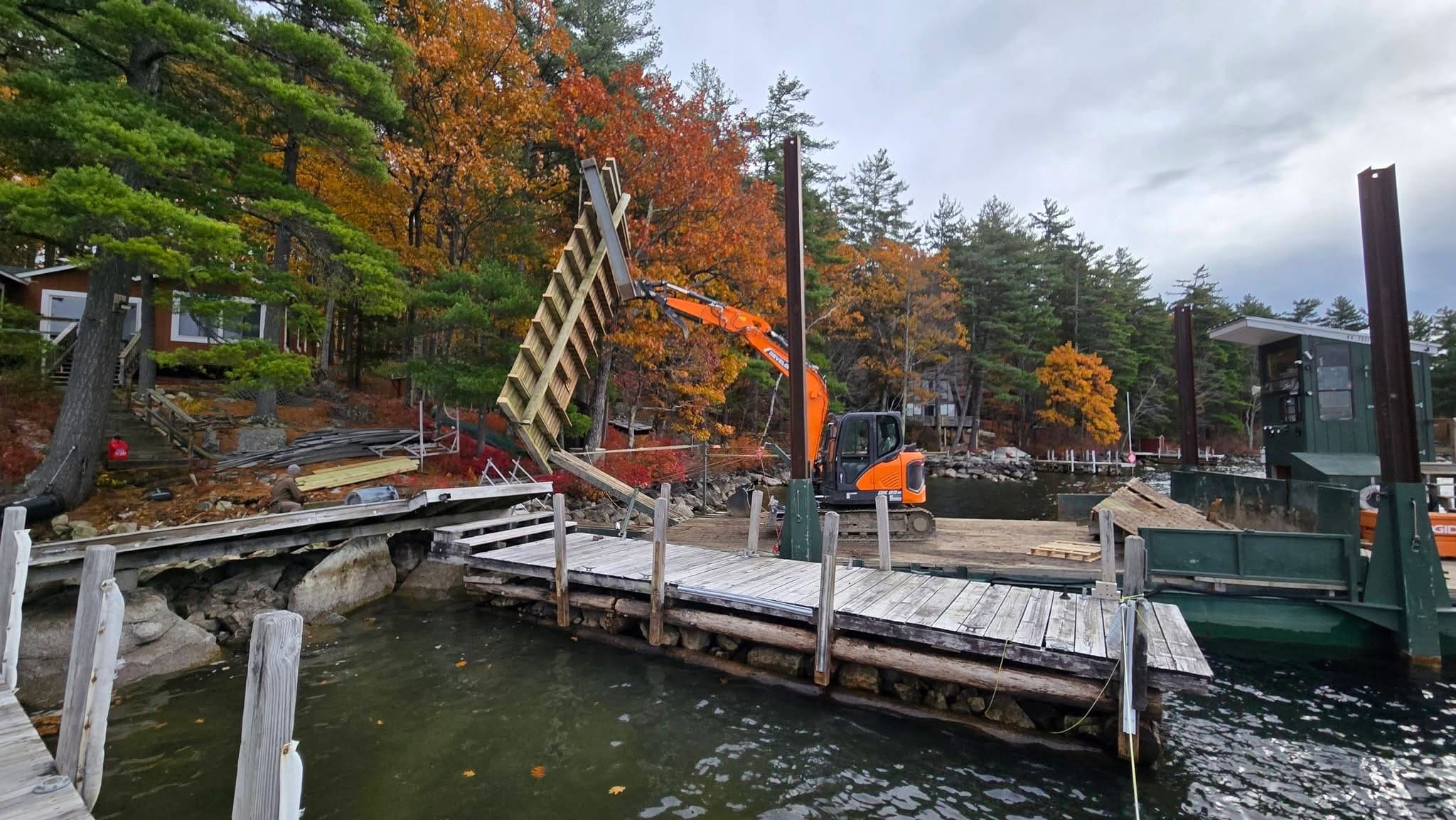 Excavator with house lift attachment loading a building section onto a barge