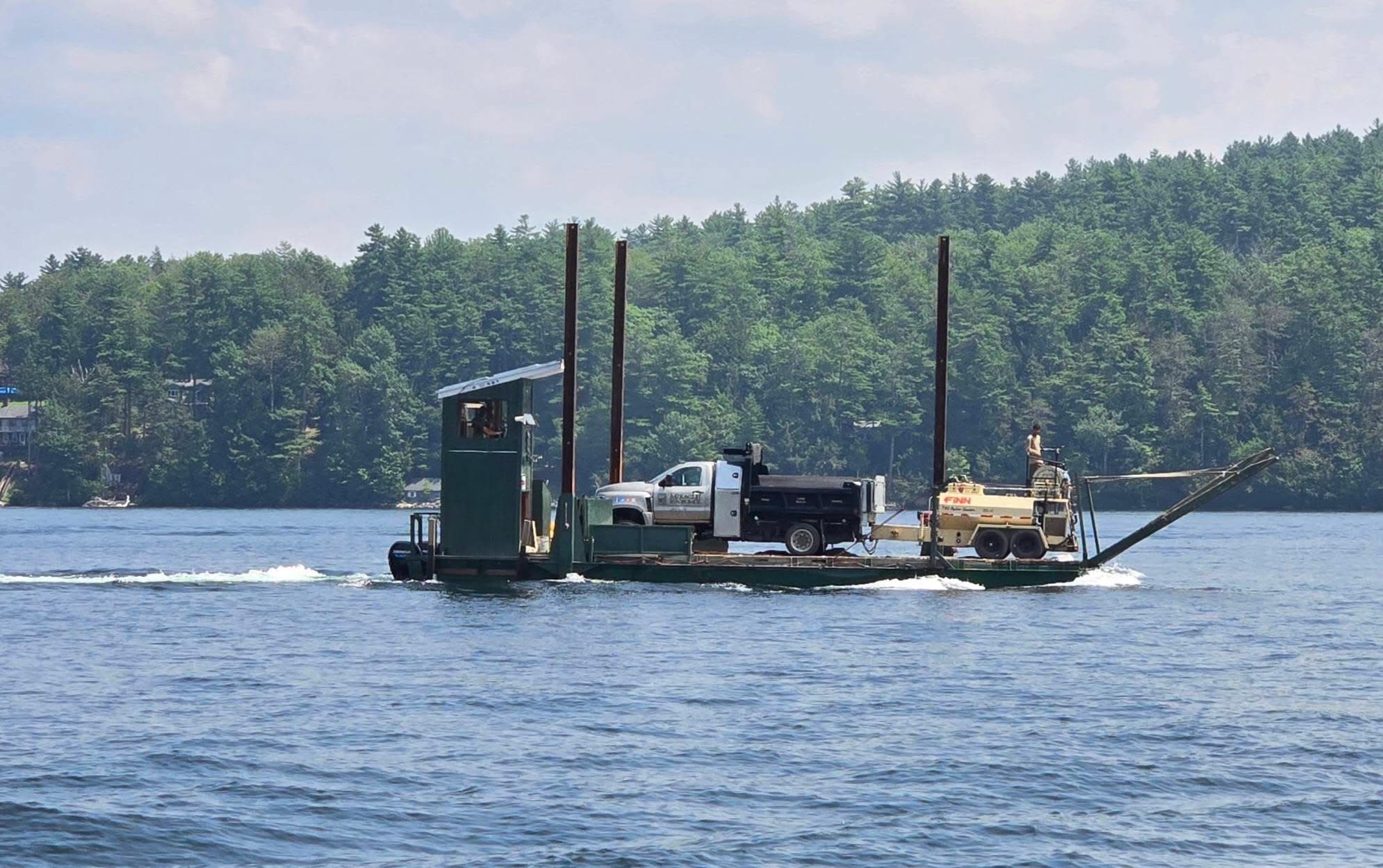Barge with truck and trailer crossing the lake on a summer day