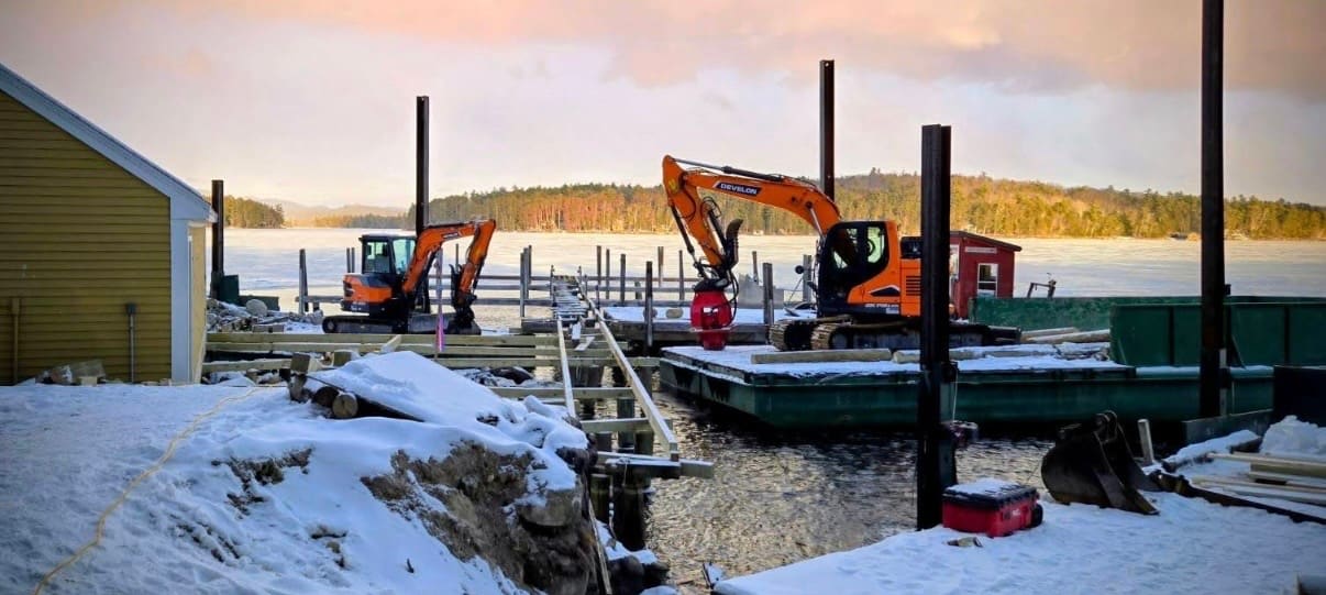 Twin excavators at work over the frozen lake at golden hour