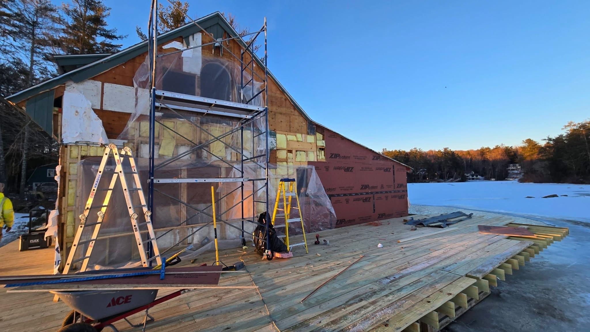 Lake house in winter with scaffolding on the side wall and new deck framing