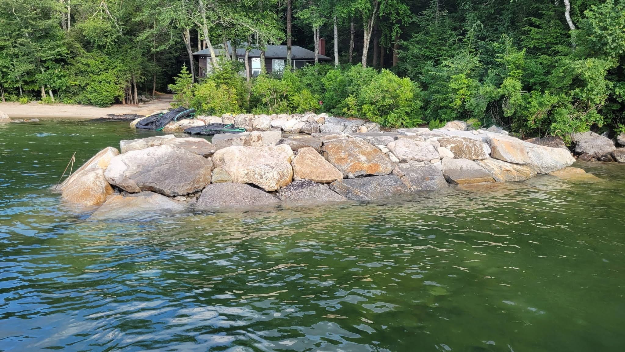 Massive boulder rip-rap installed in a cove on a clear summer day