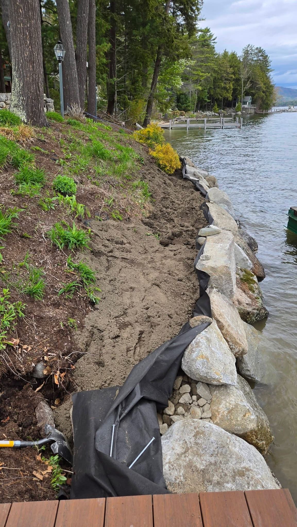 Stone retaining wall installation at the water's edge, vertical detail