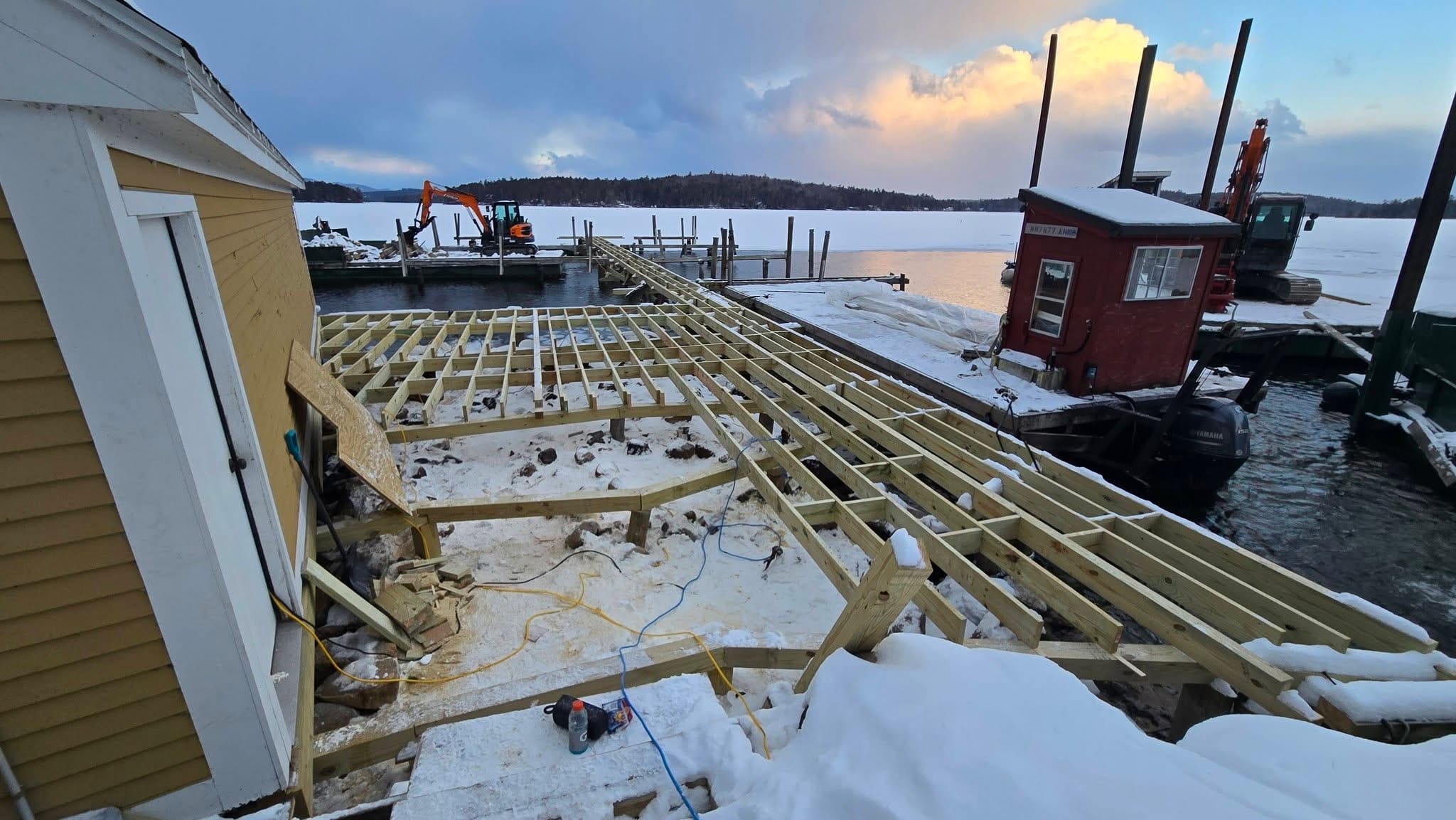 Dock framing under a dramatic winter golden-hour sky with the work shed and barge